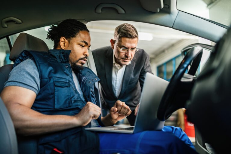 African American auto mechanic and his customer using laptop in